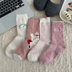 Detailed close-up of four pairs of sweet pink wool socks with cute rabbit and strawberry embroidery