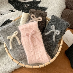 Detailed view of warm wool blend socks with bow decorations in a rustic basket
