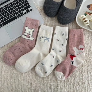 Detailed view of four pairs of sweet floral wool socks with embroidery on a cozy rug