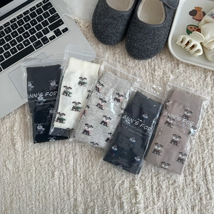 Vue à plat de chaussettes à doigts avec motif chien en cinq couleurs sur tapis blanc