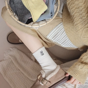 Close-up of cute cat embroidery on soft wool blend socks in various warm cream colors