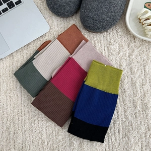 Close-up of three pairs of colorful knitted split-toe socks in various color combinations