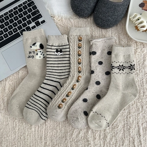 Detail of five pairs of beige Fair Isle wool socks with dog and snowflake patterns