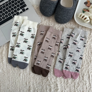 Trois paires de chaussettes Tabi à motif chien en crème, marron et gris sur un plaid