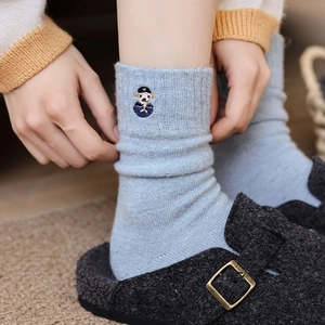 Close-up of light blue knitted socks with dog embroidery and wool Birkenstock clogs
