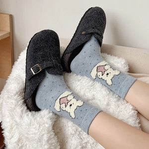 Close-up of light blue socks with cute bear embroidery and polka dots in grey felt clogs