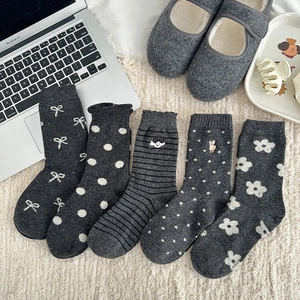 Set of five grey wool blend socks with various knit patterns on a white plush rug