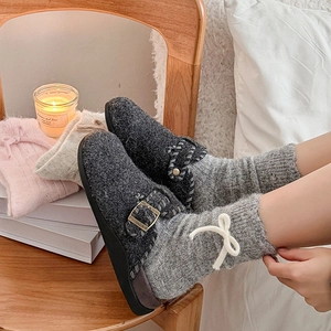 Detail of dark grey felt clog with metallic buckle and cozy home lifestyle setting