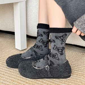 Detail of dark grey wool Mary Jane shoes paired with cute bear pattern knit socks