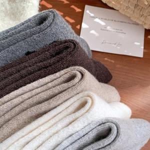 Macro shot of thick wool socks in neutral tones showing ribbed knit texture and soft fibers