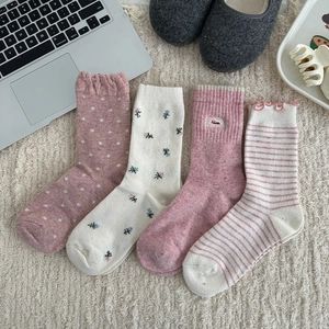 Close-up of four floral and dotted pink wool socks in a cozy home setting