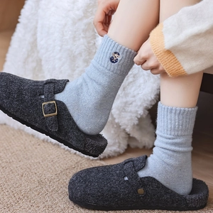 Close-up of wool felt clogs with fleece lining and embroidered knit socks in winter style