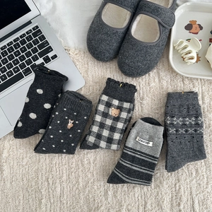 Close-up of five wool blend warm socks with Nordic patterns on a soft white rug