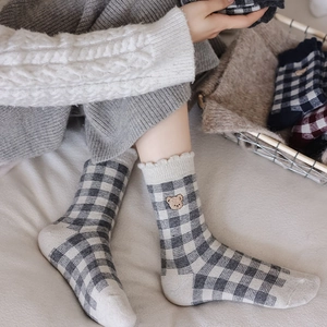 Plaid knitted socks with bear embroidery and wavy ruffles in cozy home setting