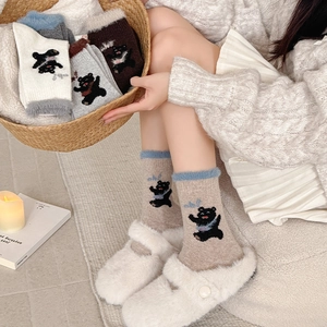 Close-up of wool socks with plush fleece cuffs and cute black bear embroidery detail