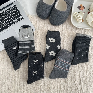 Detailed flat lay of diverse grey wool socks with polka dots and patterns on plush rug
