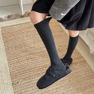 Close-up of dark grey ribbed knit calf socks paired with cozy felt mule slippers