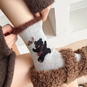 Detail of gray wool socks featuring plush brown cuffs and a cute black bear pattern