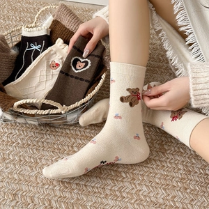 Detail of vintage brown wool socks featuring bear embroidery and cute lace bow accents