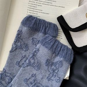 Detailed view of blue wool knit socks with vintage teddy bear jacquard pattern