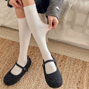 Detail of white ribbed knee-high socks showing high elasticity and soft cotton texture