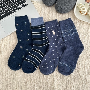 Four pairs of navy blue striped and floral wool socks for women in cozy home setting