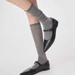 Gros plan de chaussettes en laine gris clair à bord roulé et chaussures Mary Jane