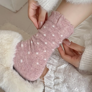 Close-up of pink polka dot wool socks with ruffled cuffs and thick knit texture