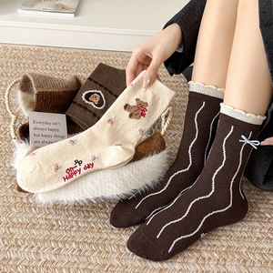 Detailed bear embroidery and bow accents on thick brown wool socks for winter