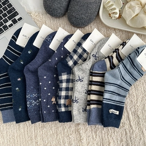 Flat lay of multiple mid-calf wool socks featuring stripes and floral patterns