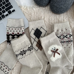 Close-up of Fair Isle knit wool socks with dog patch and bow on a soft rug