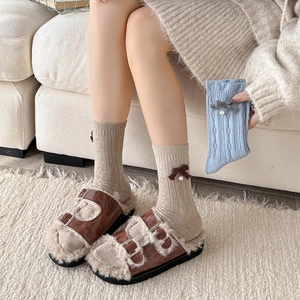 Winter wool socks with bow and pearls paired with cozy brown plush slippers on a rug