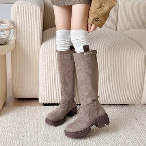 Detail of white cable knit over-the-knee socks paired with taupe suede high boots