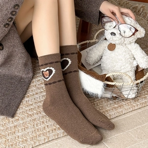 Detail of vintage brown wool socks featuring an embroidered bear inside a white heart