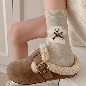 Detail of plush brown suede slippers with buckle and grey socks with puppy design