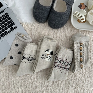 Flat lay of 5 pairs of beige wool socks with Nordic patterns and cute dog embroidery