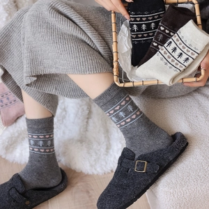 Detail of wool blend knit crew socks with Fair Isle tree and heart patterns in a basket