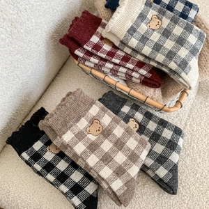 Close-up of winter knit socks featuring plaid patterns and bear embroidery in a wire basket