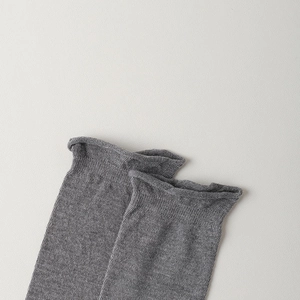 Gros plan détaillé du bord roulé et de la texture en tricot gris des chaussettes