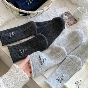 Close-up of ribbed knit wool socks with heel embroidery and stylish rolled cuffs