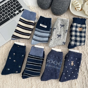 Flat lay of 8 styles of warm knit socks with stripes, bears, and bow embroidery details