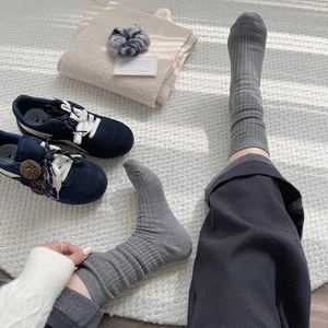 Close-up of gray ribbed knit crew socks with elastic cuffs on a cozy white rug
