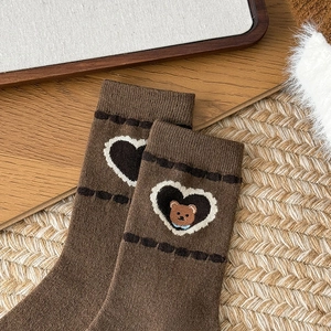Detailed view of brown knit wool socks featuring embroidered bear and heart patterns