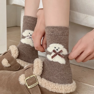 Detail of wool socks with white plush puppy pattern and red plaid bow decoration