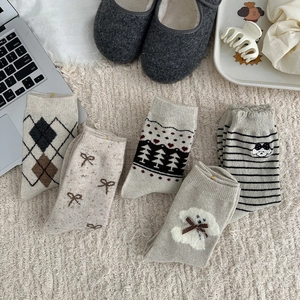 Flat lay of five thick wool Fair Isle socks with dog embroidery and bow details