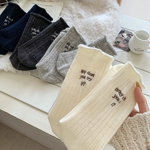 Detailed close-up of ribbed wool socks with letter embroidery in various fall colors