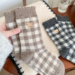 Detailed view of plaid mid-calf socks featuring cute bear embroidery and ruffled edges