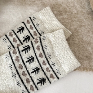 Detail of wool socks showing black pine tree and brown heart jacquard knit patterns
