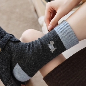 Close-up of cute dog embroidery on dark grey and light blue thick knit wool socks