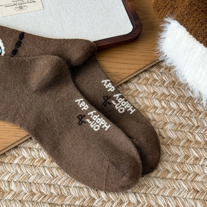 Close-up of brown wool socks with Oh Happy Day print and knitted texture detail